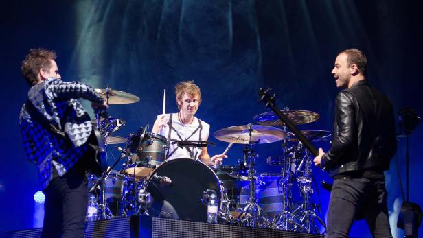 Eine Band spielt live auf einer Bühne mit blauem Licht.