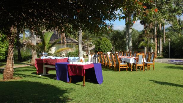 Ein gedeckter Tisch und Stühle stehen auf einer grünen Wiese für eine Veranstaltung bereit.