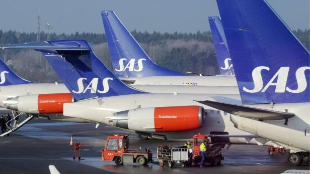 Mehrere Flugzeuge der Fluggesellschaft SAS stehen auf einem Rollfeld.
