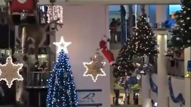 Weihnachtsdekorationen mit Weihnachtsbäumen, Sternen und einem Weihnachtsmann in einem Einkaufszentrum.