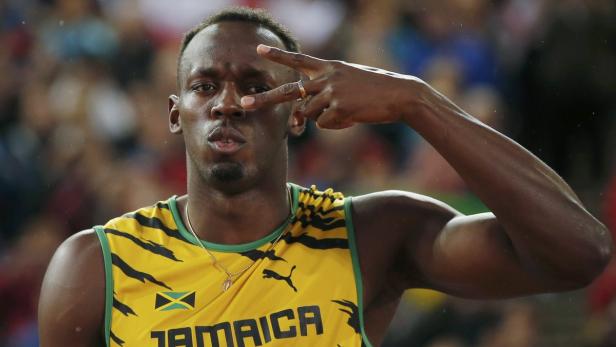Usain Bolt posiert mit einem Victory-Zeichen vor seinem Gesicht.