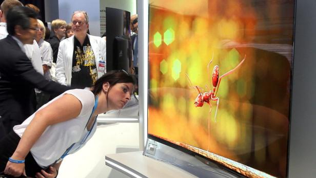 epa03856152 Visitors look at ultra flat bent TV screens in the halls at the Berlin Radio Show IFA in Berlin, Germany, 07 September 2013. The IFA, a leading international trade fair of Consumer Electronics and Home Appliances, is open to the public from 06 until 11 September 2013. EPA/WOLFGANG KUMM