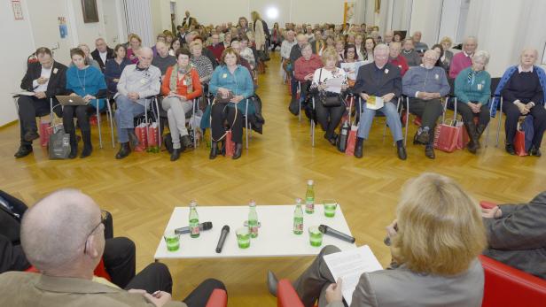 Ein Publikum sitzt bei einer Veranstaltung in einem Raum.