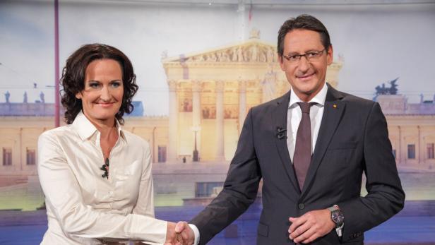 Eine Frau und ein Mann geben sich vor dem Wiener Rathaus die Hand.