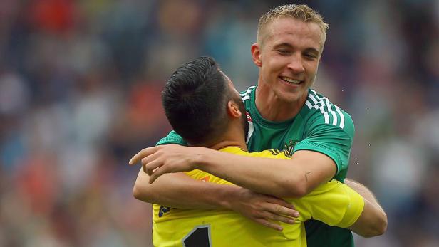 Zwei Fußballspieler umarmen sich auf dem Spielfeld.