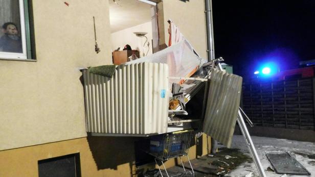 Ein durch eine Explosion beschädigter Balkon eines Wohnhauses bei Nacht.