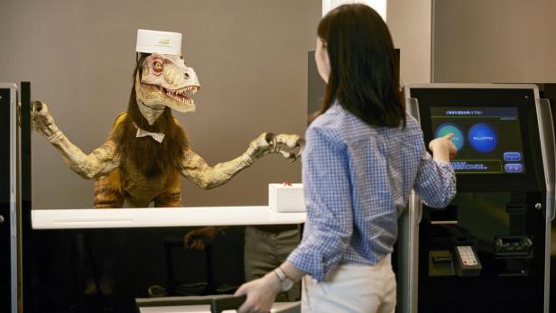 Ein Gast checkt in einem japanischen Hotel bei einem Dinosaurier-Roboter ein