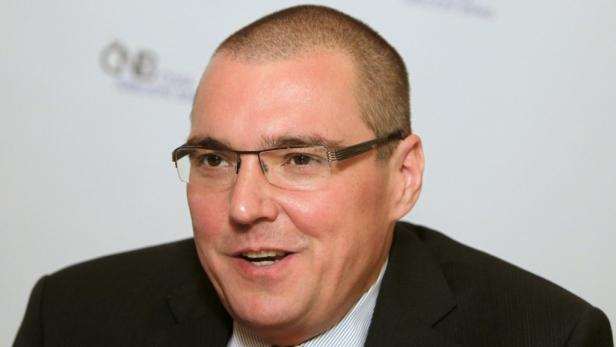 Ein Mann mit Brille und Anzug lächelt.