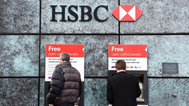 Zwei Personen heben an Geldautomaten einer HSBC-Bank Bargeld ab.