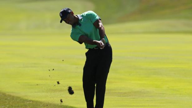 Tiger Woods schlägt einen Golfball auf einem grünen Golfplatz.