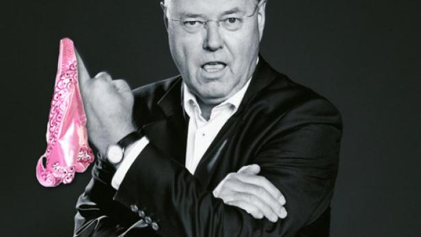 Ein Mann im Anzug hält einen pinkfarbenen Damenslip hoch und wirkt dabei missbilligend.