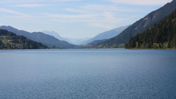 Der Haldensee liegt eingebettet zwischen bewaldeten Bergen.