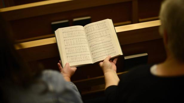 Eine Person hält ein aufgeschlagenes Gesangbuch in den Händen.