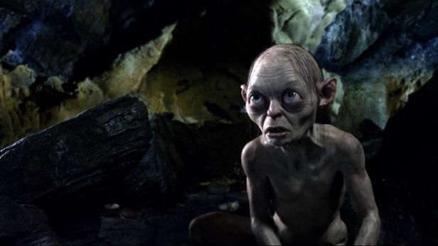 Gollum sitzt in einer dunklen Höhle und blickt mit großen Augen nach oben.