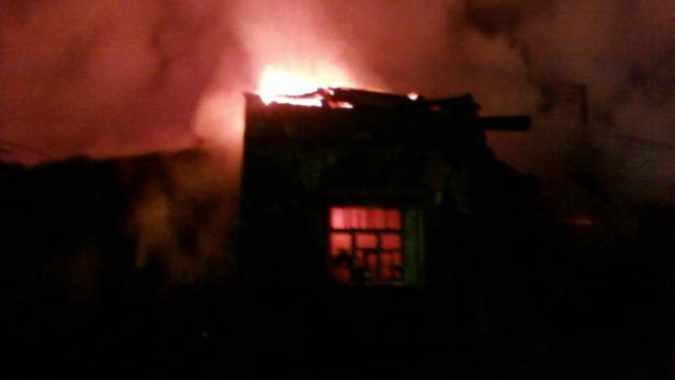 Ein Haus steht in Flammen, dichter Rauch steigt auf.