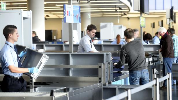 Ein Sicherheitsbeamter kontrolliert das Gepäck von Reisenden am Flughafen.