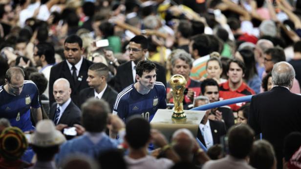 Lionel Messi geht mit dem WM-Pokal durch eine Menschenmenge.