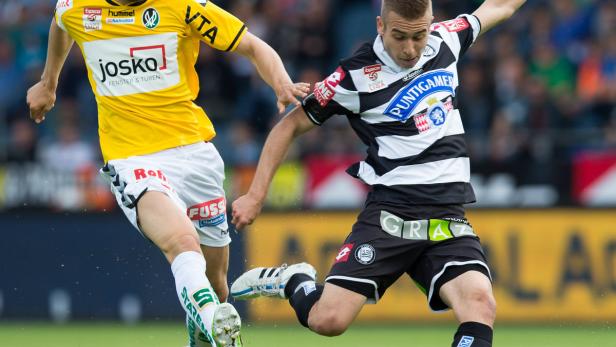 Zwei Fußballspieler kämpfen um den Ball auf dem Spielfeld.