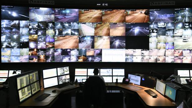 Ein Überwachungsraum mit einer Person vor vielen Monitoren, die Autobahnaufnahmen zeigen.
