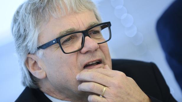 Ein Mann mit Brille und grauem Haar berührt sein Kinn.
