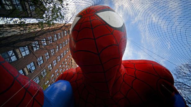 Ein großer, aufblasbarer Spider-Man vor einem Gebäude und blauem Himmel.