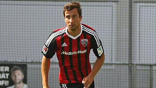 Ein Fußballspieler in einem rot-schwarz gestreiften Trikot mit dem Logo von Media Markt.