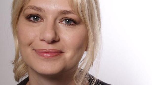 Porträt einer lächelnden Frau mit blonden Haaren.