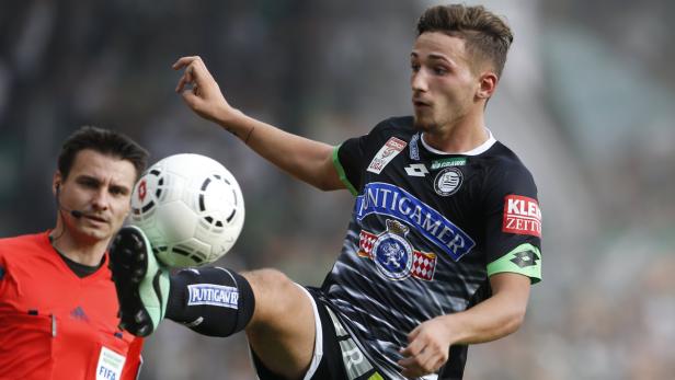 Ein Fußballspieler jongliert den Ball mit dem Fuß, während ein Schiedsrichter zusieht.