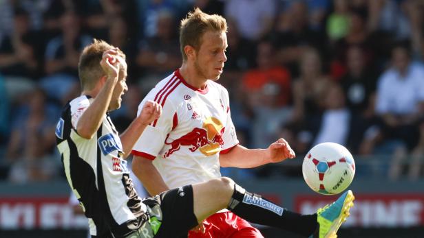 Zwei Fußballspieler kämpfen um den Ball während eines Spiels.
