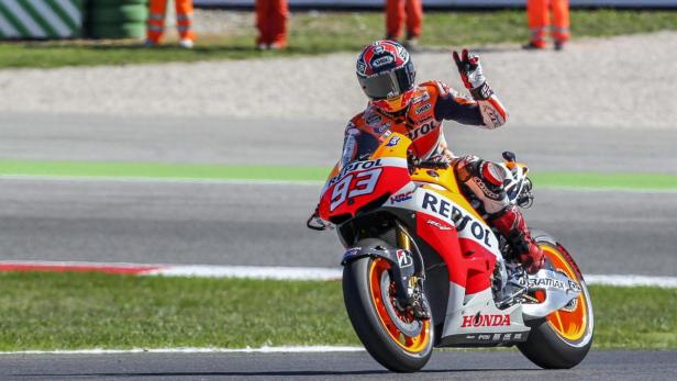Ein Motorradrennfahrer auf einer Honda mit der Nummer 93 winkt dem Publikum zu.
