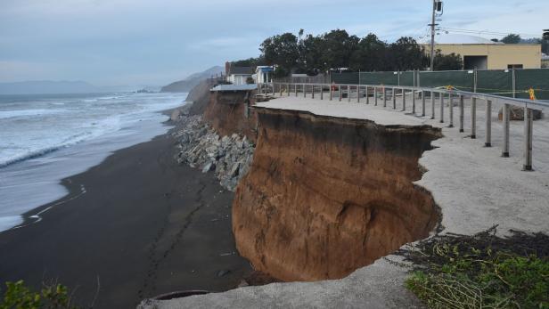 Ein Küstenabschnitt mit starker Erosion und beschädigter Uferpromenade.