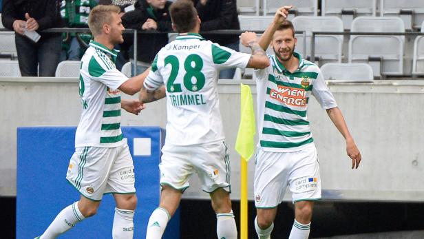 Drei Fußballspieler von Rapid Wien feiern ein Tor.