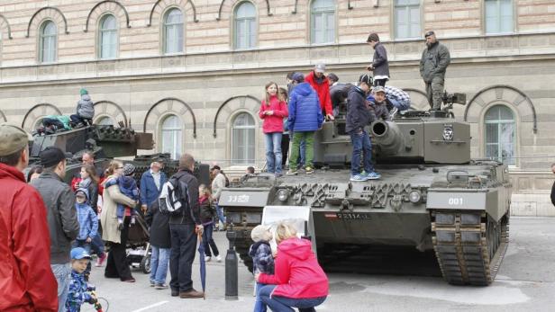 Eine Gruppe von Menschen, darunter viele Kinder, betrachtet und erklimmt einen Panzer.