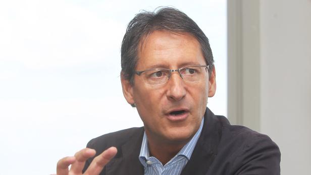 Ein Mann mit Brille und blau gestreiftem Hemd gestikuliert.