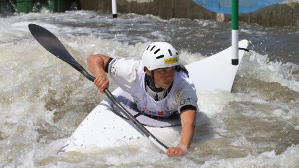 Eine Kanutin kämpft sich mit einem Paddel durch das aufgewühlte Wasser.