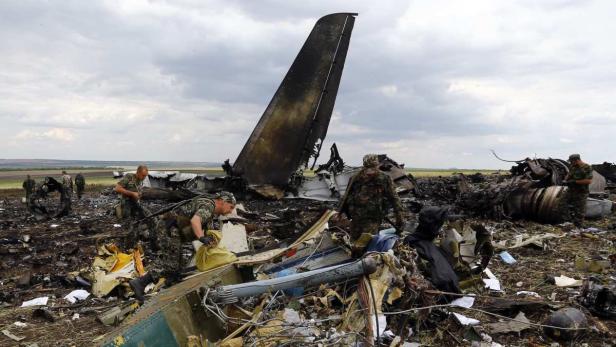 Prorussische Separatisten stehen an der Seite des zerstörten, ukrainischen Transportflugzeuges vom Typ Iljuschin IL-76.