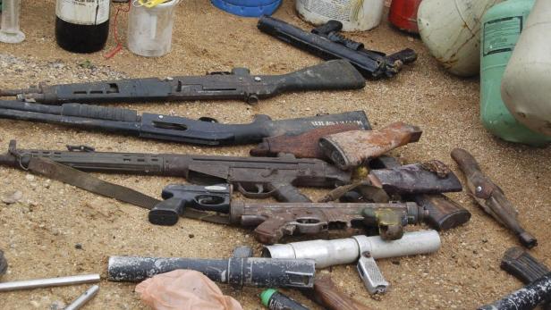 Mehrere alte und verrostete Waffen liegen auf dem Boden.