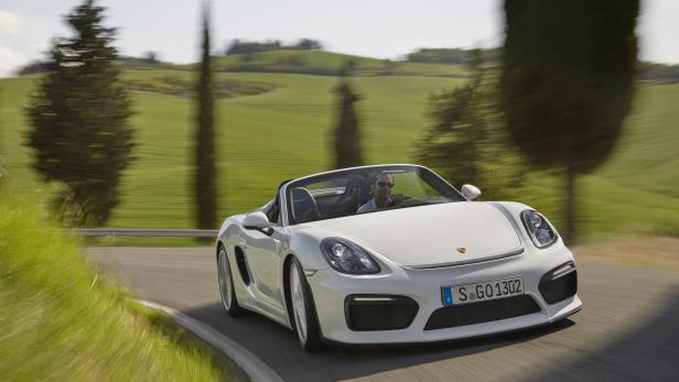 Ein weißer Porsche Boxster Spyder fährt auf einer Landstraße.