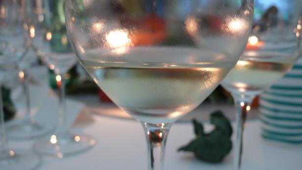 Ein gedeckter Tisch mit Weingläsern, gefüllt mit Weißwein.