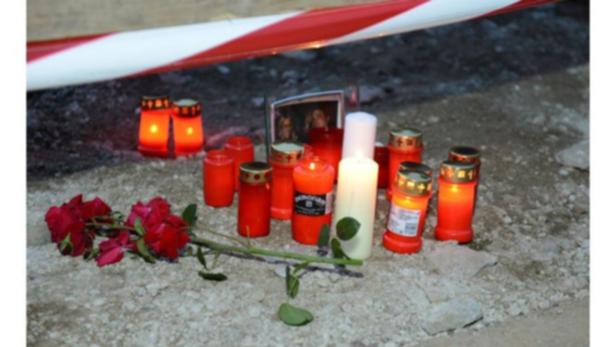 Am Straßenrand liegen rote Rosen und brennende Kerzen als Zeichen des Gedenkens.