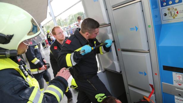 Feuerwehrleute öffnen mit Werkzeug ein Schließfach, möglicherweise um eine Person zu retten.