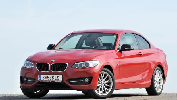 Ein roter BMW der 2er-Reihe steht auf einer ebenen Fläche.