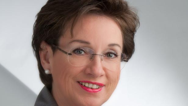 Porträt einer lächelnden Frau mit Brille und Ohrringen.