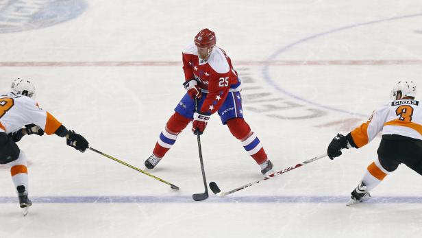 Ein Eishockeyspieler in roter Uniform mit der Nummer 25 wird von zwei Gegenspielern umringt.