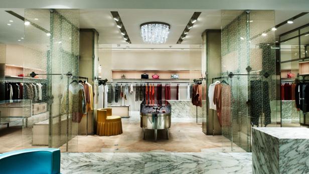 Blick in ein luxuriöses Bekleidungsgeschäft mit Kleidung, Accessoires und Marmorboden.