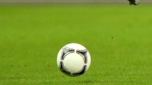 Ein Fußball schwebt über einem grünen Rasen.