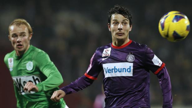 Zwei Fußballspieler während eines Spiels, einer in Lila, der andere in Grün.