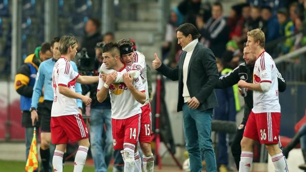 Zwei Fußballspieler umarmen sich, während der Trainer den Daumen hochhält.