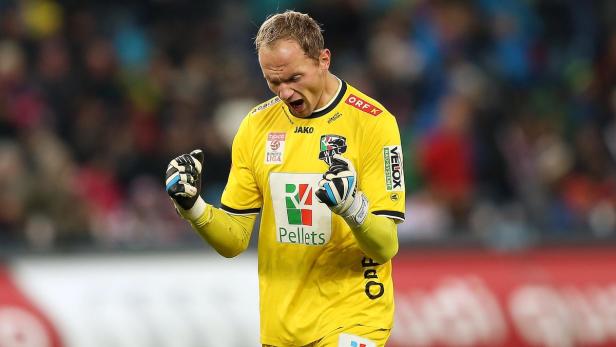 Ein Torwart in gelber Spielkleidung jubelt mit geballten Fäusten.