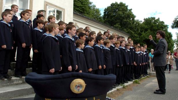 Ein Knabenchor singt unter der Leitung eines Dirigenten.